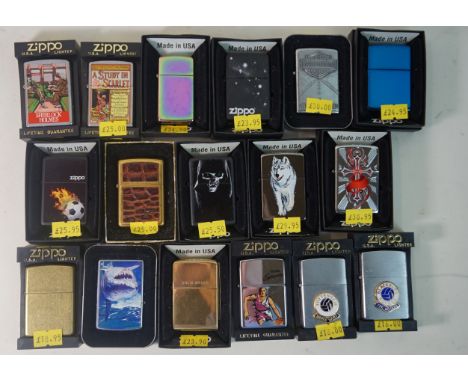 Sixty three assorted Zippo lighters and rotating shop display cabinetVarious designs to include 'The Beatles', '70th Annivers