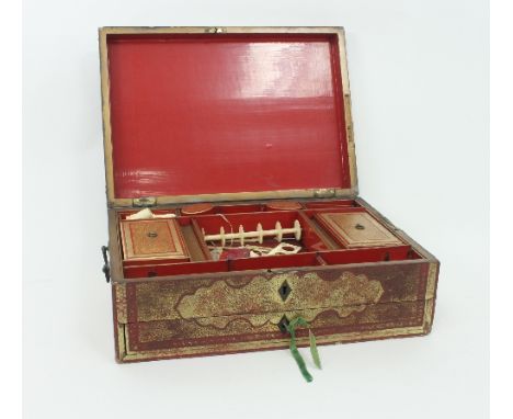 An Eastern red lacquer work box, highlighted in gilt and with carry handles to the sides, the hinged cover enclosing a fitted
