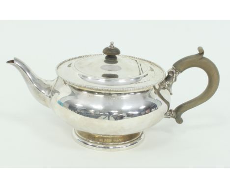 A silver circular teapot, W N Ltd., Birmingham 1922, with beaded border and boxwood handle, approximately 590gm Condition Rep