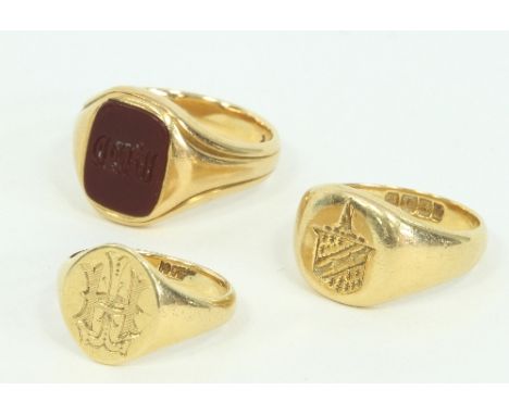 Three gentlemen's 18ct gold signet rings, one engraved with a family crest, the other with a monogram; and a cornelian signet