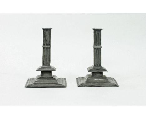 A pair of square based pewter candlesticks, with fluted square stick with drip trays, initialled I.W. beneath, 22.5cm high/No