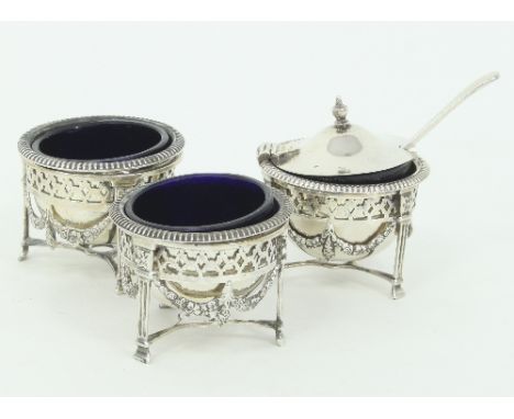 A three-piece silver cruet set, W & FR Birmingham 1938, comprising two open salts and a mustard pot with blue glass liners, a