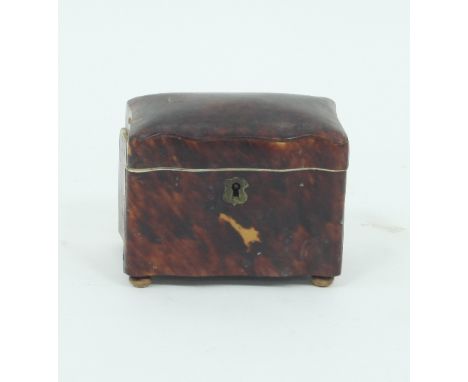 A small tortoiseshell tea caddy of serpentine outline on bun feet, enclosing two lidded compartments (damages), 11.5cm wide