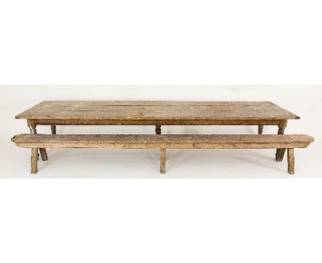 A pine kitchen table, with three-plank top on turned tapering leg, 421.75cm long with a matching bench/Note: from the servant