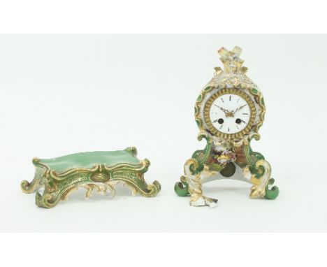 A French porcelain clock case, mid 19th Century, of scrolling foliate outline highlighted in gilt on a green ground, together