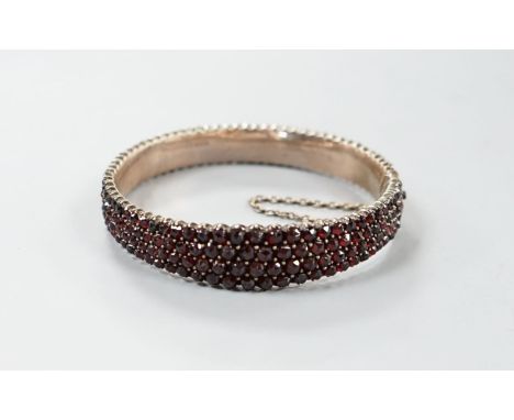 A late Victorian gilt white metal and garnet encrusted hinged bangle (stone missing).