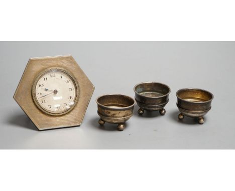 A silver mounted easel strut timepiece and three George V silver salt cellars.