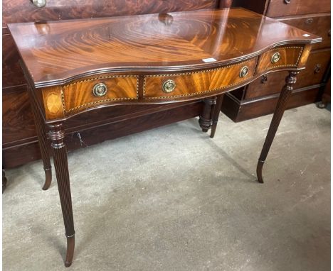 A Regency style inlaid mahogany three drawer serpentine console table 