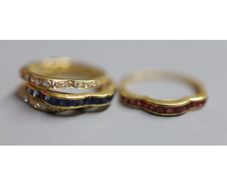A modern continental 750 yellow metal and triple shank, sapphire, ruby and diamond set shaped half eternity ring, with interc
