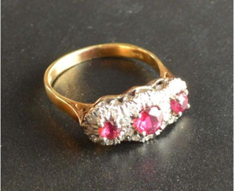 An 18 Carat Gold Ruby and Diamond Ring of Triple Cluster Form set with three rubies surrounded by diamonds within a pierced s