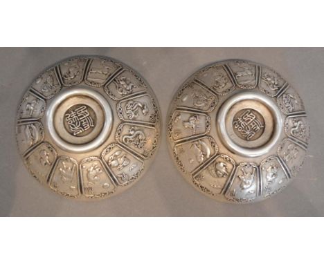 A Pair of Chinese White Metal Dishes decorated in relief with reserves depicting animals, seal marks to base, 10.5cm diameter