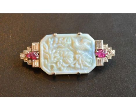 An Art Deco Opal Diamond and Ruby Set brooch, the carved opal panel flanked by carved rubies and baguette diamonds mounted in