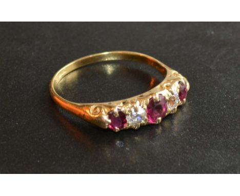 An 18 Carat Gold Ruby and Diamond Ring set with three rubies and two diamonds within a pierced setting 