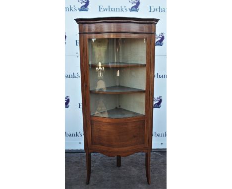 Edwardian mahogany and line strung serpentine front corner cabinet, with single glazed door enclosing shelves and vacant shel