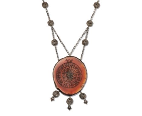 A CARNELIAN ISLAMIC VERSE PENDANT NECKLACE, the large oval agate engraved with Islamic verse, suspending three pendant drops,
