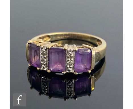 A 9ct hallmarked amethyst and diamond ring, three emerald cut claw set amethysts spaced by a single diamond, weight 3g, ring 