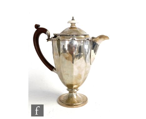 A hallmarked silver pedestal coffee pot of plain faceted form with castellated border, wooden scroll hand an ivory button fin