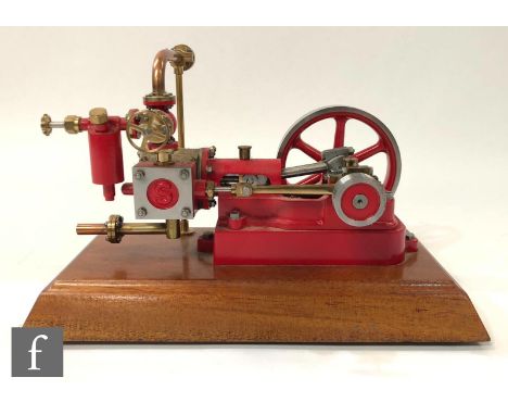 A Stuart single cylinder horizontal engine, painted red with six spoked flywheel, raised to a mahogany plinth, height 15cm, w