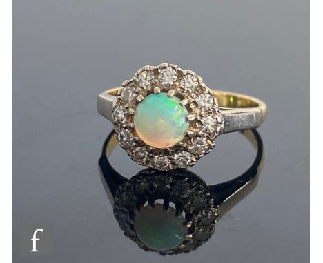 An 18ct hallmarked opal and diamond cluster ring, central circular claw set opal within a twelve stone diamond surround, weig