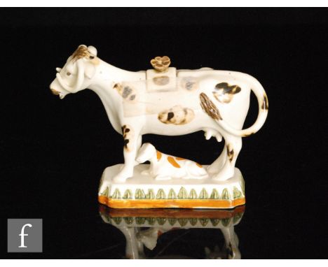 A late 19th to early 20th Century Staffordshire Prattware cow creamer and cover with recumbent calf beneath, cow with brown s