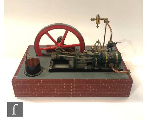 A single horizontal cylinder engine with governor and six spoked flywheel painted in red with chain drive, raised to a faux b