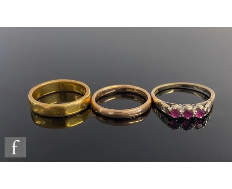 A 22ct wedding ring, weight 5.9g, with a 9ct example, weight 2.2g, and a 9ct three stone ruby ring, weight 2.1g. (3) 