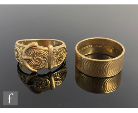 A 9ct hallmarked buckle ring with a 9ct wide wedding ring, total weight 15.5g, sizes X and U respectively. (2) 