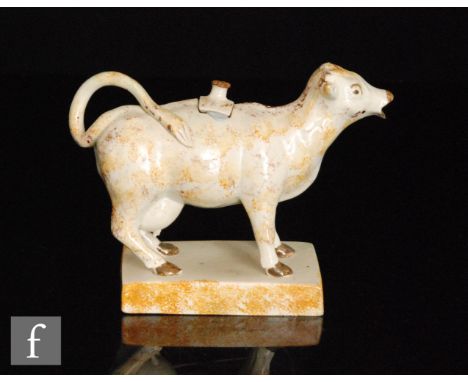A late 18th to early 19th Century Staffordshire pearlware cow creamer and cover, with ochre and manganese sponged decoration,