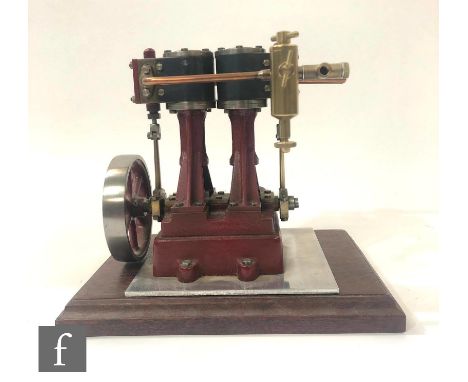 A vertical twin cylinder marine engine, painted in maroon with six spoked flywheel, with detached stepped base, height 17cm, 
