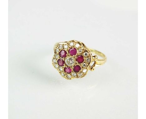 A ruby and diamond floral cluster ring, designed as a central brilliant cut diamond claw set within a border of six round mix