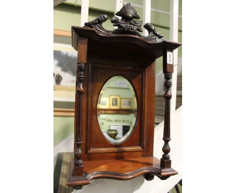 A first quarter 20th century mahogany hanging display shelf with carved crest twin turned column front insert with a oval bev