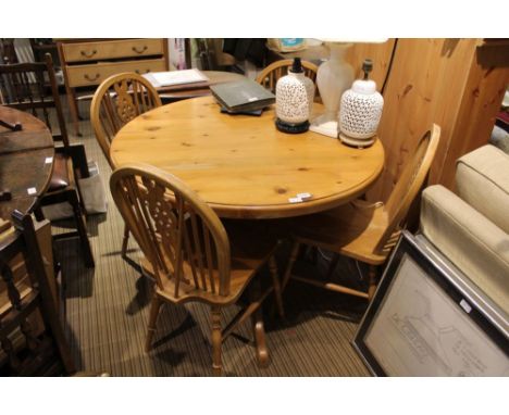 A pine kitchen suite comprising circular topped pedestal table and four wheel and stick back solid seated chairs 