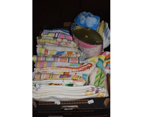 A box full of colourful vintage towels and tea towels, some still having original packaging.