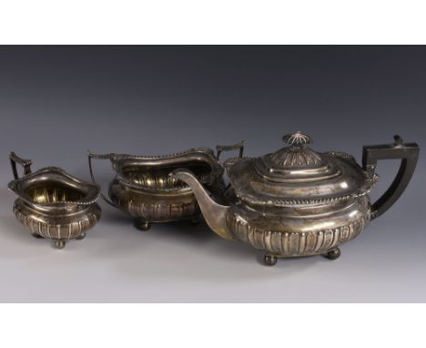 A George V silver three piece half fluted boat shaped tea service, comprising teapot, milk jug and sugar basin, hinged domed 