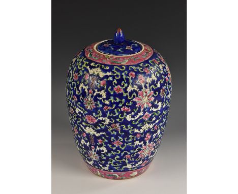 A Chinese ovoid jar and cover, brightly painted in polychrome with flowers and scrolling leaves, on a blue ground, bud finial