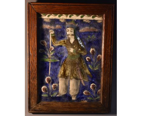 A Persian rectangular tile, decorated in the Iznik palette with an armed chief, wearing flowing robes, blossoming flowers on 