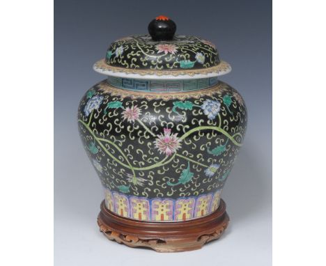 A Chinese ginger jar and cover, painted in colourful polychrome with peonies and lilies on a black ground, the neck with mean