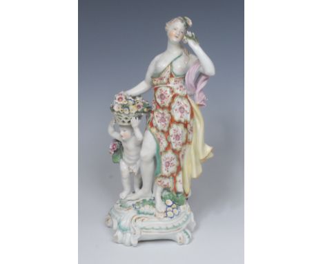 A Derby Patch Mark figure, Emblematic of Spring, she standing beside a with a basket of flowers on his head she sniffing a fl