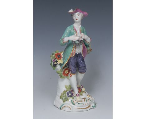 A Derby Patch Mark figure, of a man, wearing a broad brimmed hat, turquoise jacket, purple breeches, holding a bird's nest, s