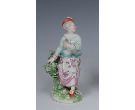 A Derby Patch Mark figure,  of Columbine, Harlequin's companion , standing in twisted motion holding a flower, wearing a feat