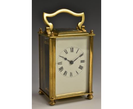 An early 20th century brass carriage clock, with Roman numerals, bevelled glass panels, swing handle, bun feet, 13cm high, mo