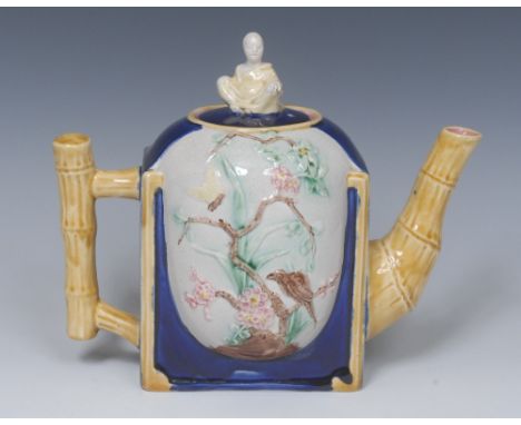 A Victorian Majolica teapot, in relief with bird and butterfly on blossoming branches, on a cobalt blue ground, mustard bambo