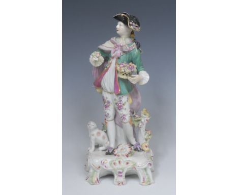 A Derby Pale Period Patch Mark figure,  of a Dresden Shepherd,  standing and holding a basket of fruit and a small flower spr