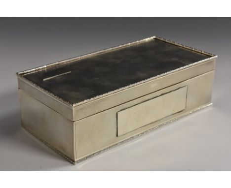 An Art Deco silver rectangular table cigarette box, engine turned overall, hinged cover, leafy scroll borders, cedar lined, 1