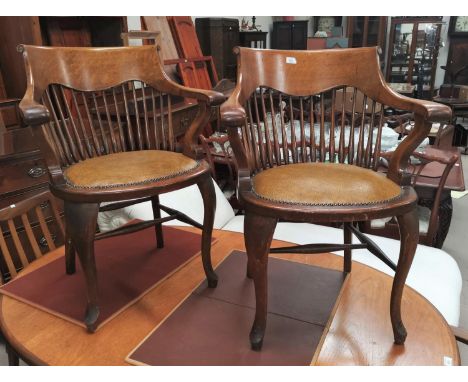 A pair of early 20th century oak stick back smokers bow arm chairs with studded tan coloured seats on cabriole legs 