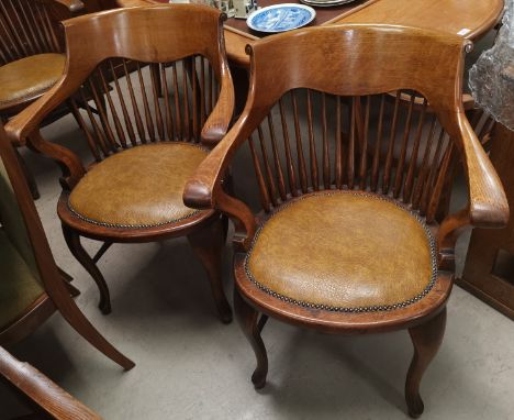 A pair of early 20th century oak stick back smokers bow arm chairs with studded tan coloured seats on cabriole legs 