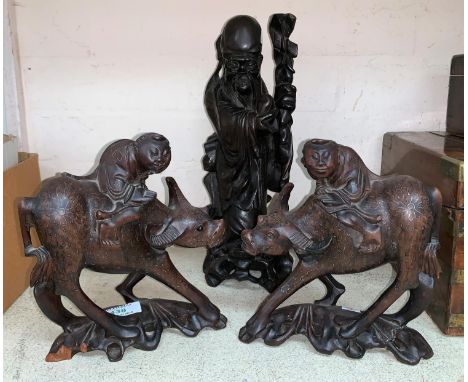 A 19th century Chinese pair of carved hardwood figures: boys on buffalos, with silver wire inlay; a similar figure of an immo