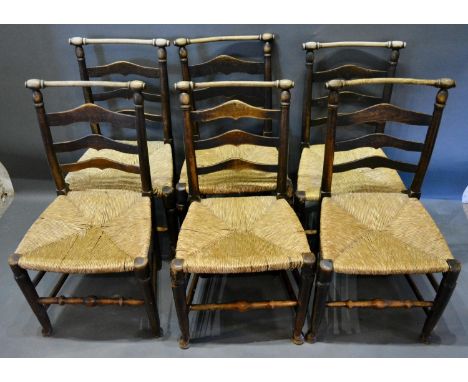 A Set of Six Elm Dining Chairs, the ladder backs with turned top rail above rush seats raised upon turned legs with stretcher