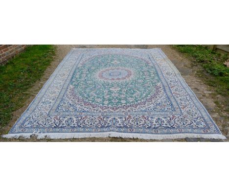 A North West Persian Woollen Carpet with a central medallion within an allover design upon a cream, red and blue ground withi