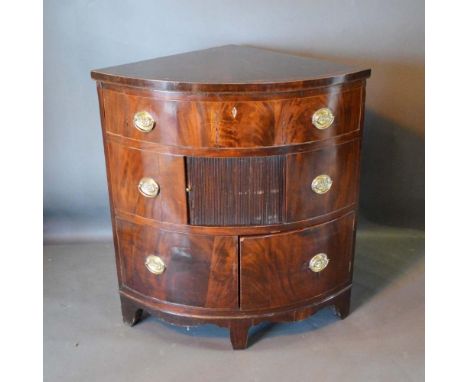 A 19th Century Mahogany Corner Cabinet with a drawer above a tambour and two doors with oval brass handles raised upon bracke